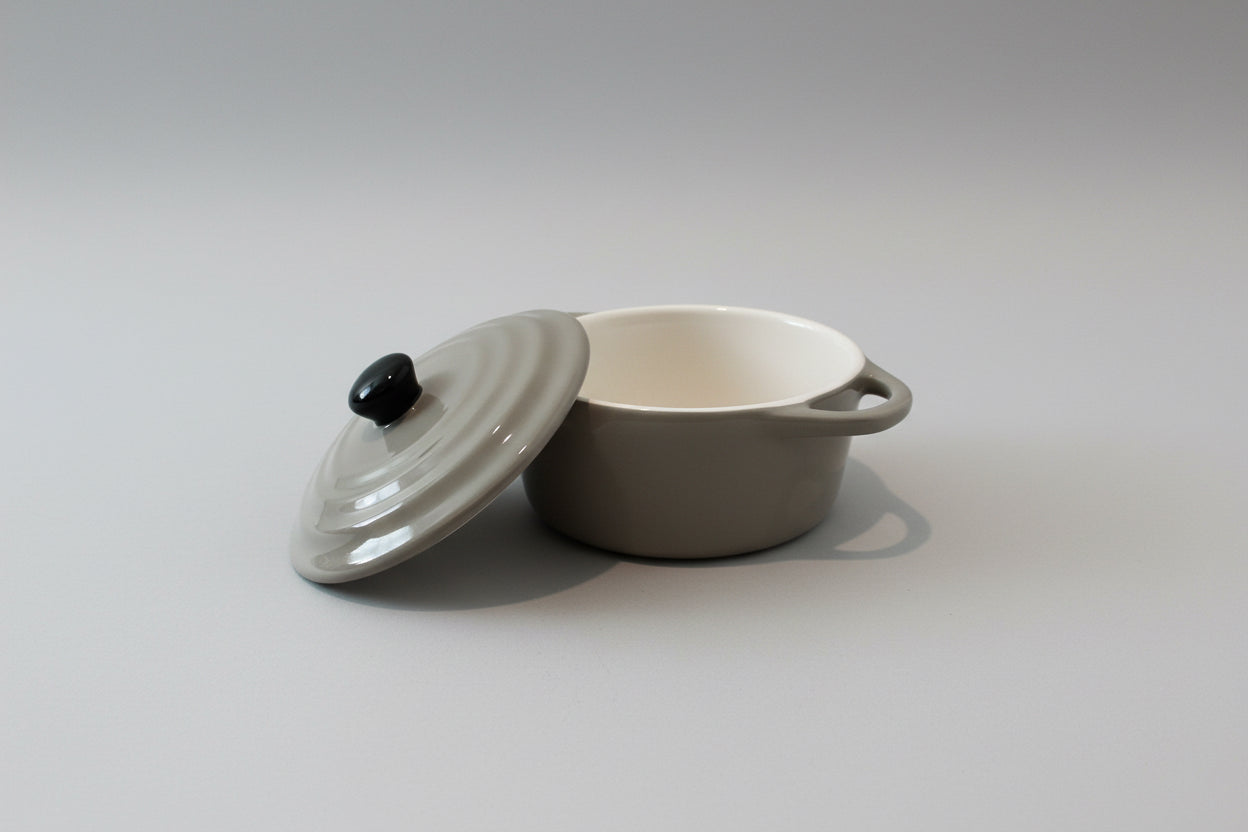 Round beige object with a handle on a pink surface